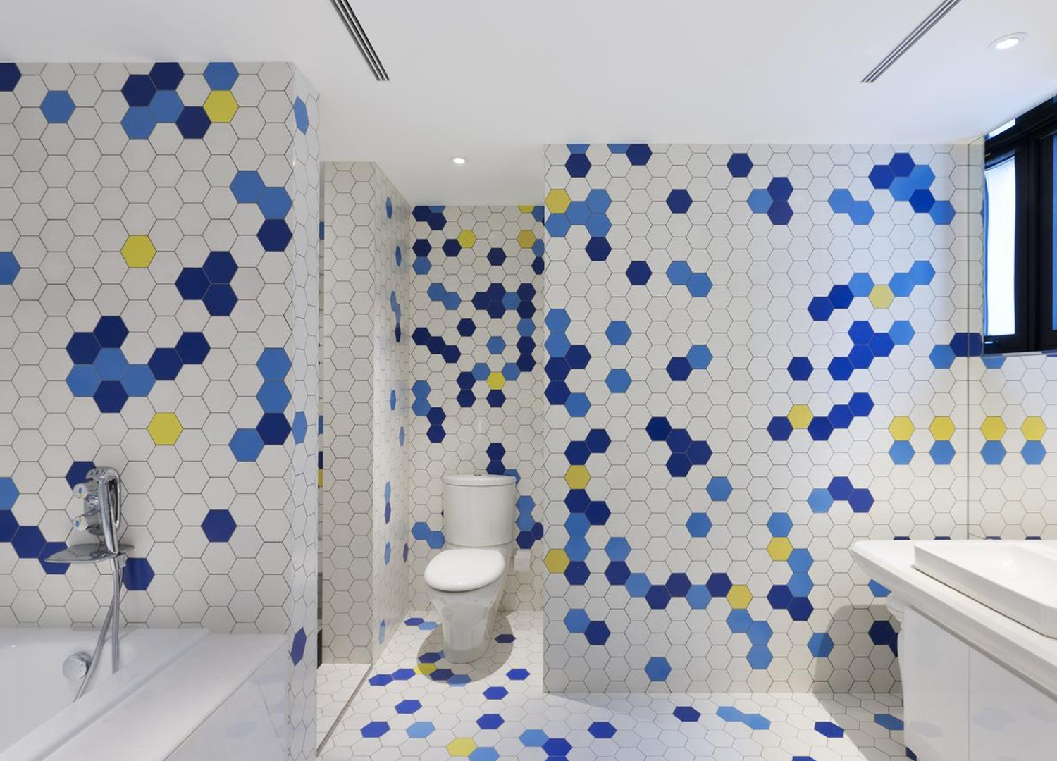 整体卫浴间由六边形马赛克瓷砖构成，空间明亮大气。布局兼顾浴缸、淋浴房、洗漱区，合理设计，非常自然清爽。